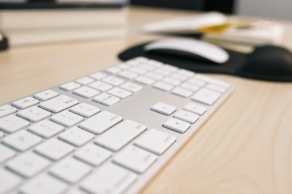 Closeup of Mac keyboard with mouse and sketchbook in background • Photo by Mary-Ann Zykin