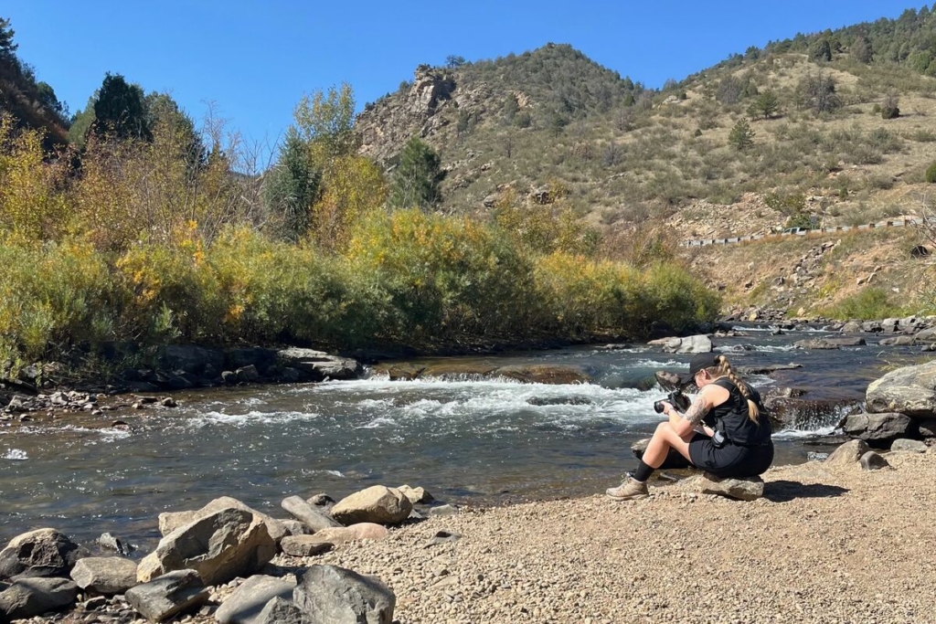 Mary-Ann Zykin taking a photo of a river in front of a mountain in Colorado