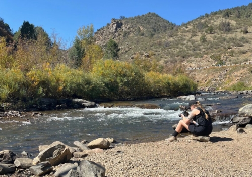 Mary-Ann Zykin taking a photo of a river in front of a mountain in Colorado