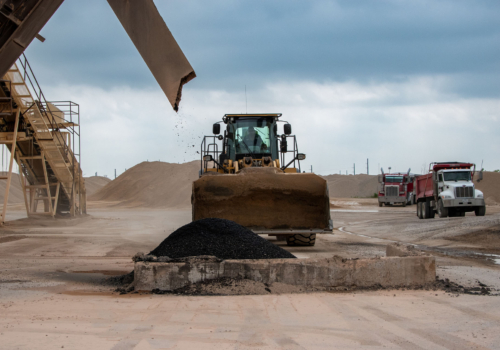 Asphalt being poured with a bulldozer in the background