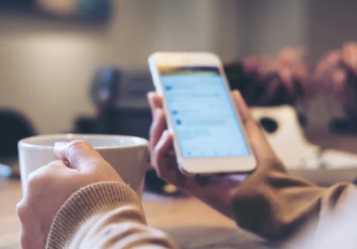 Person holding a cell phone and a mug