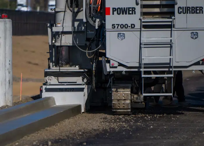 Concrete slip form curb machine in action