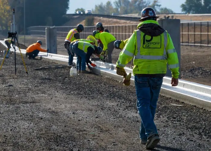 Concrete construction worker walking toward a freshly poured curb