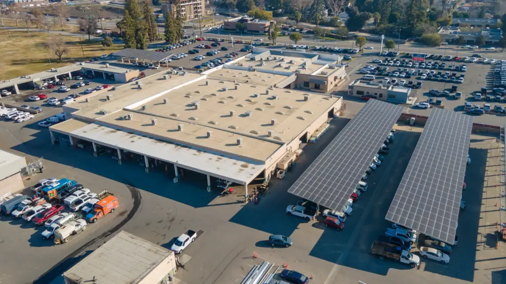An aerial view of a car dealership with cars parked outside and solar panels.