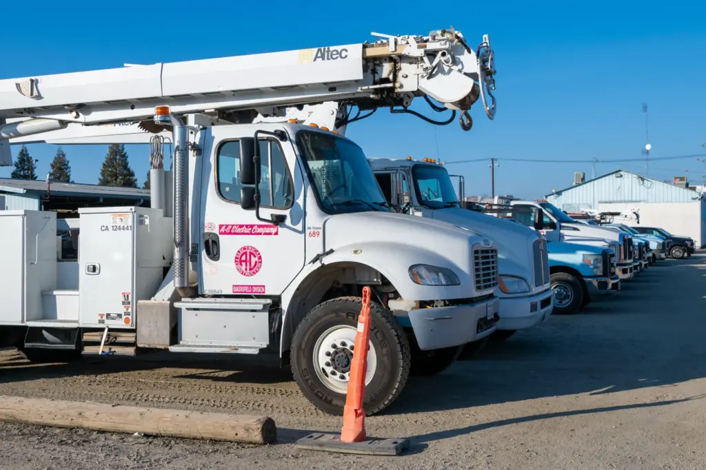 Lineup of electrical construction trucks in parking lot.