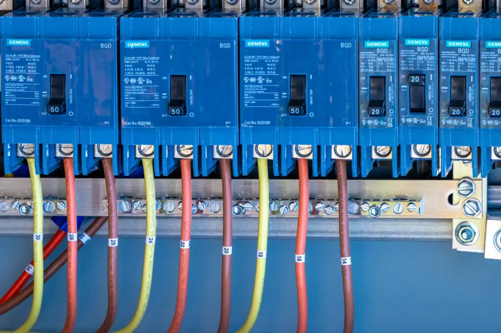 A series of electrical breakers with various colored wires connected to them.