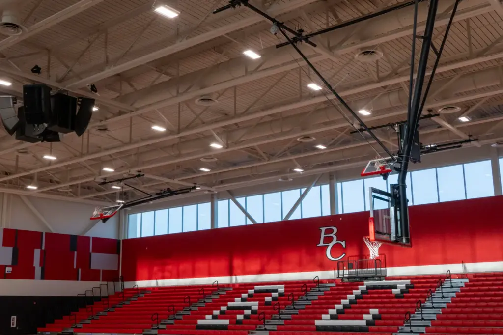 An indoor basketball court with red seats and white walls.