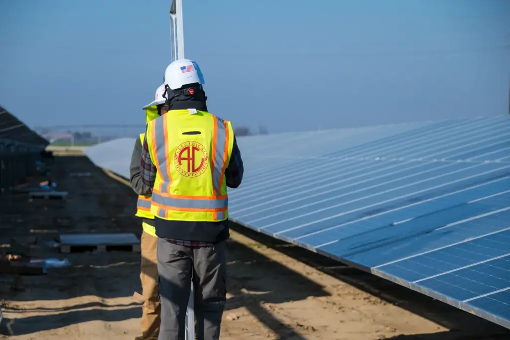 Two workers installing solar panels outdoors with a clear sky and blue background.