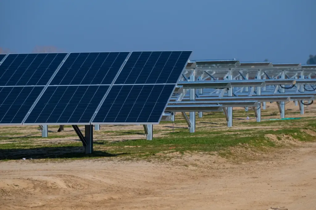 Solar panels installed on poles with dirt ground and sky background.
