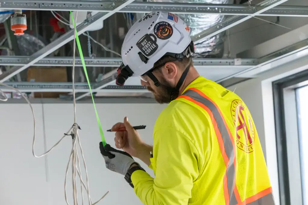 An electrical construction worker is working with tools and equipment at a building site.