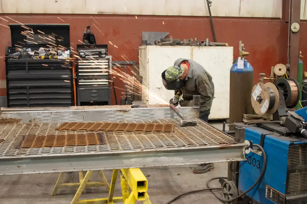 A person welding a metal table with sparks flying around them.