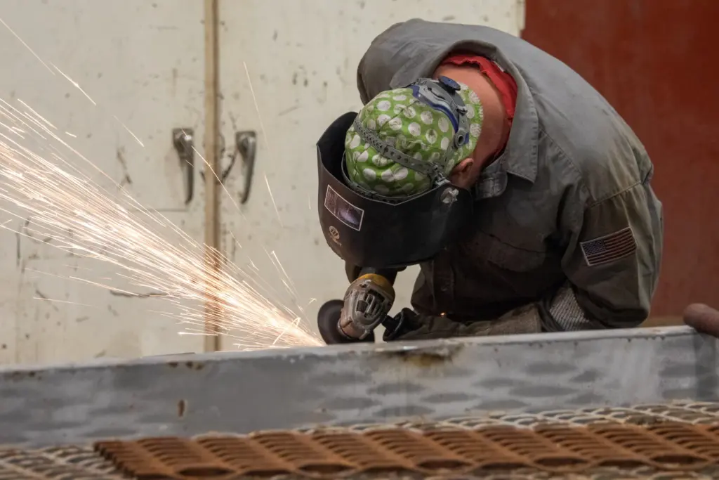 A person welding a metal table with sparks flying around them.
