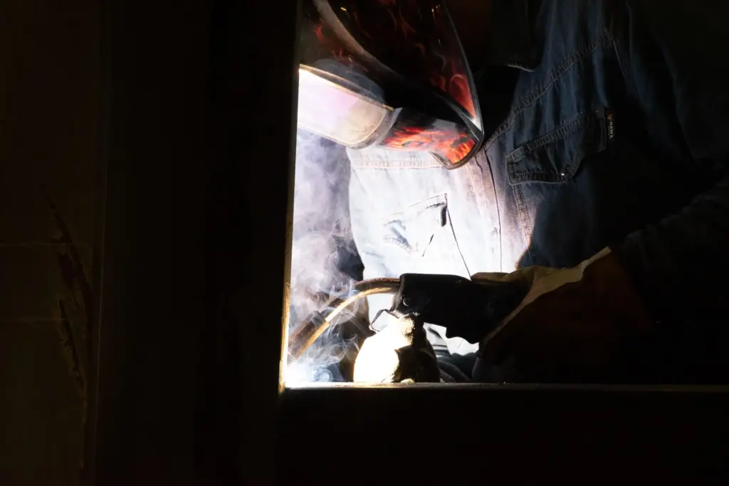 A person welding with smoke and light from the torch.
