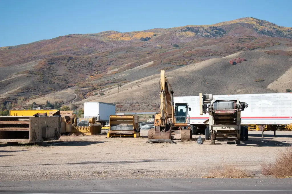 A construction site with machinery and dirt mounds under a clear sky.