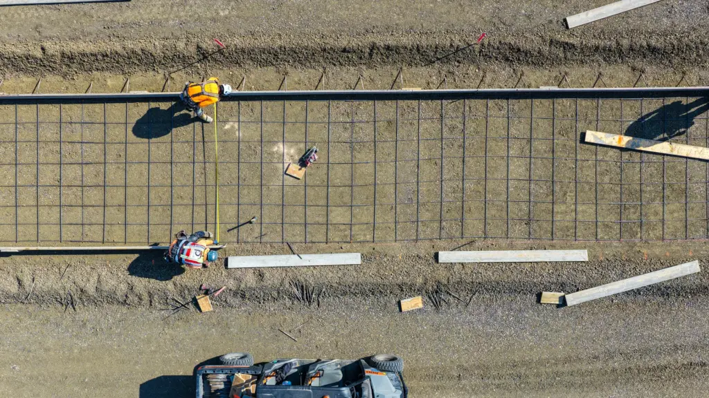 Construction workers are working with concrete and rebar at a construction site.