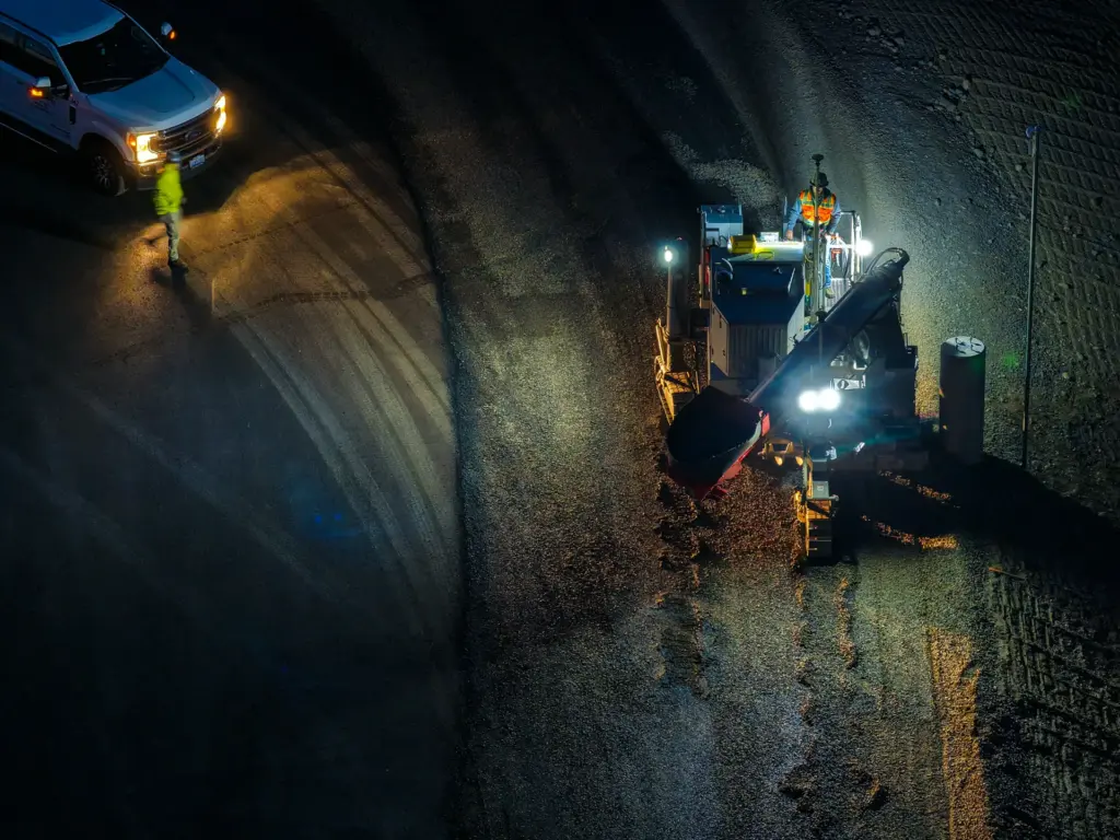 An aerial view of a concrete curb machine at night.
