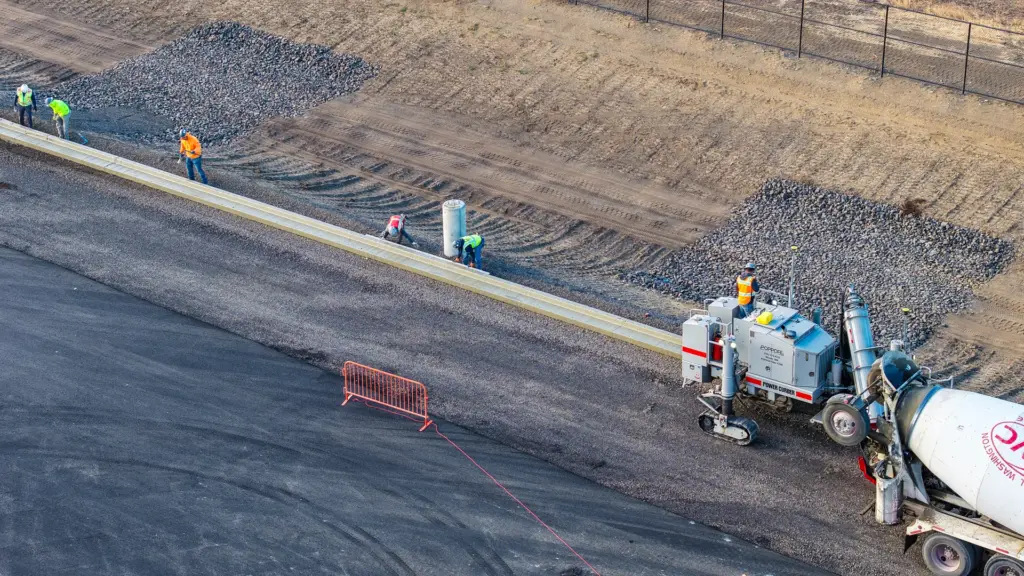 An aerial view of a construction site with concrete curb machine and workers.