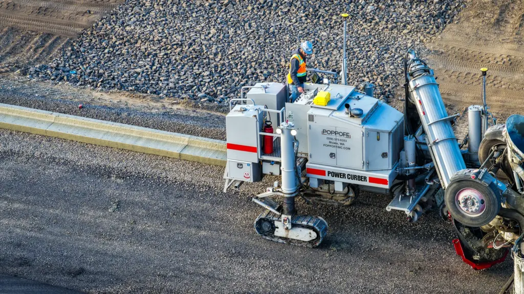 An aerial view of a construction site with concrete curb machine and workers.