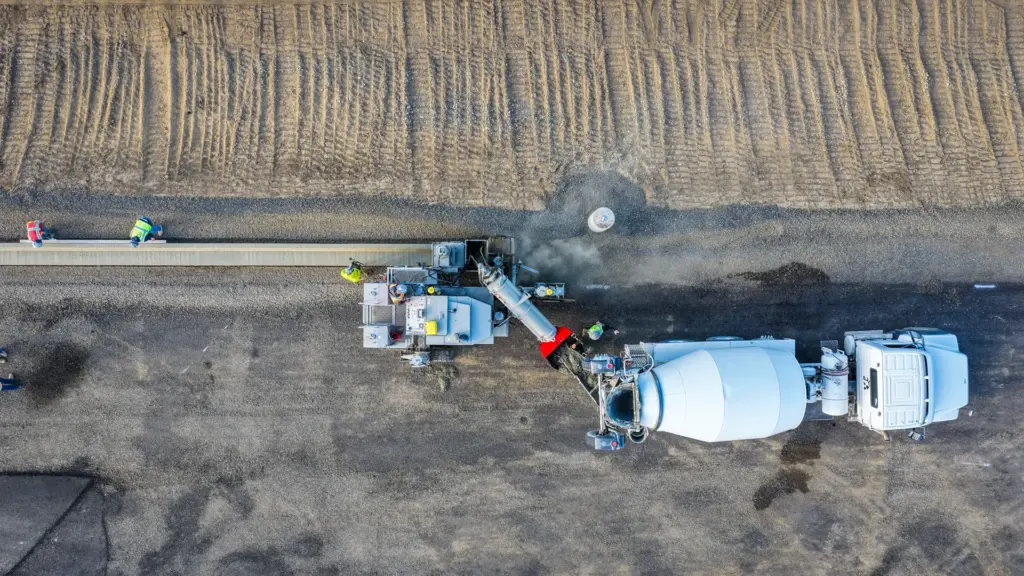 An aerial view of a construction site with concrete curb machine and workers.