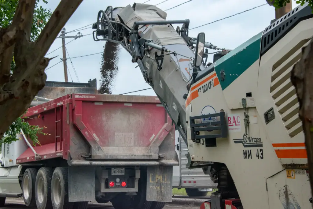 A road reclamation machine is dumping old road aggregate into a dump truck.