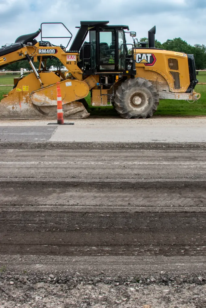 A CAT heavy equipment vehicle is parked near a construction site with orange traffic cones and dirt road.