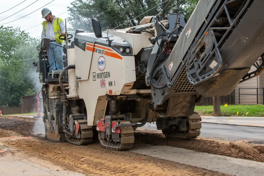 A construction worker driving a road reclamation machine.
