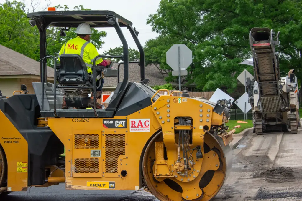 A person is driving a yellow CAT RAC truck during roadway construction project.