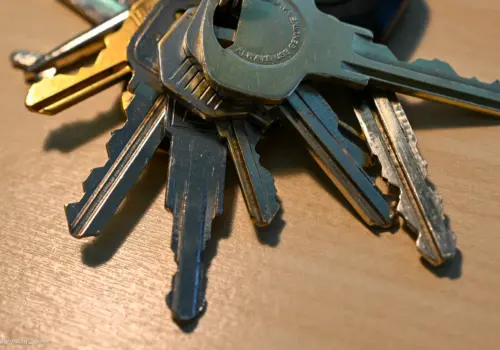 A set of keys sitting on a wooden desk.