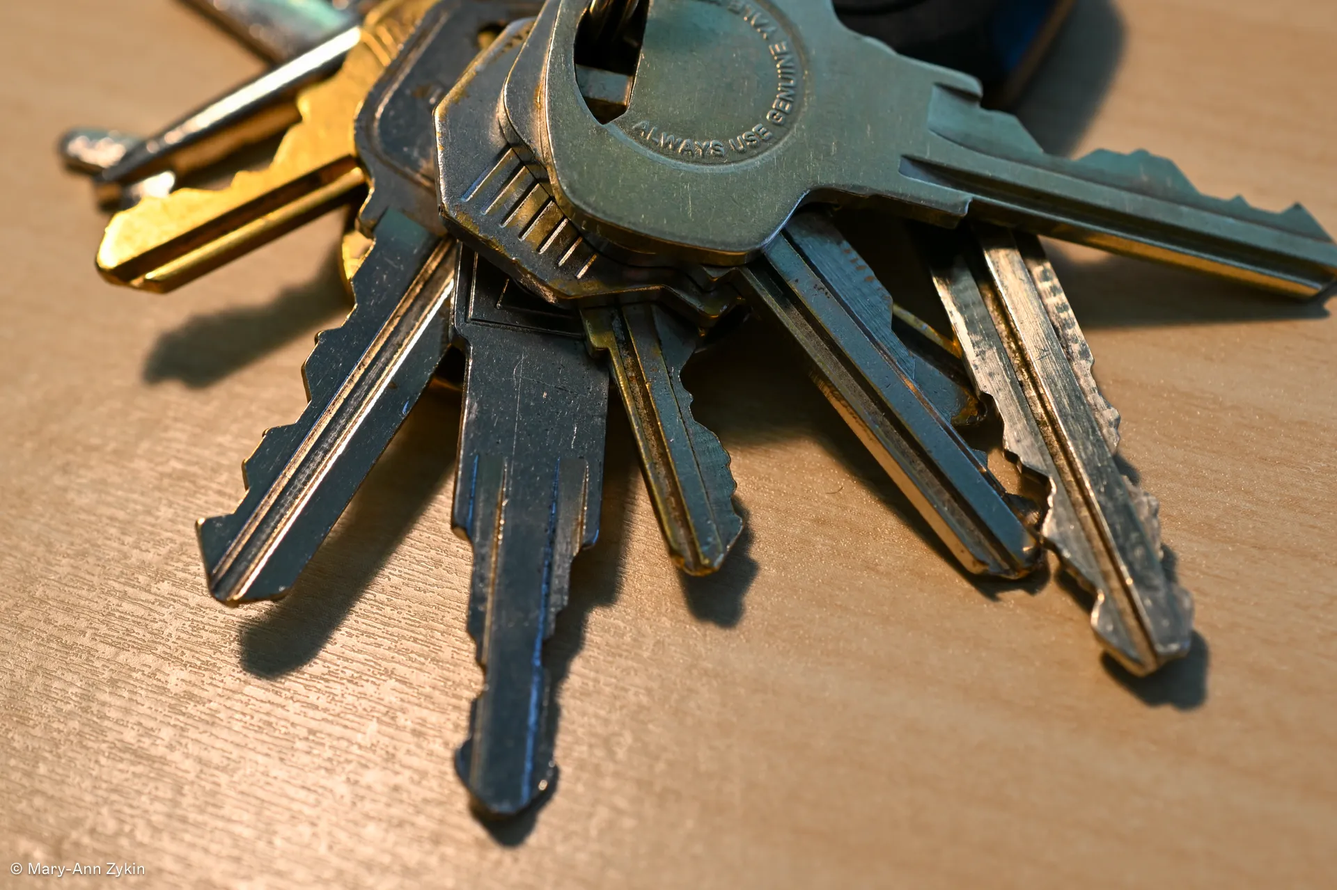 A set of keys sitting on a wooden desk.